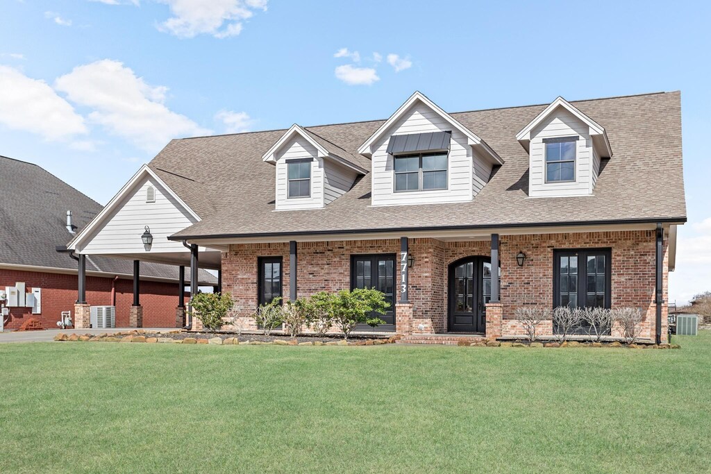 7713 Holmes Rd, Nederland, TX 77627 - view of front of home featuring a front yard, cooling unit, and brick siding