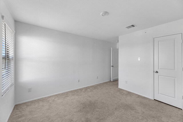 unfurnished room featuring baseboards, visible vents, and light colored carpet