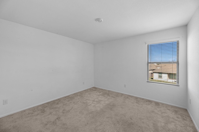 carpeted empty room featuring baseboards