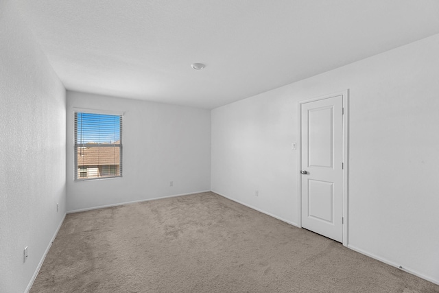 carpeted empty room featuring baseboards