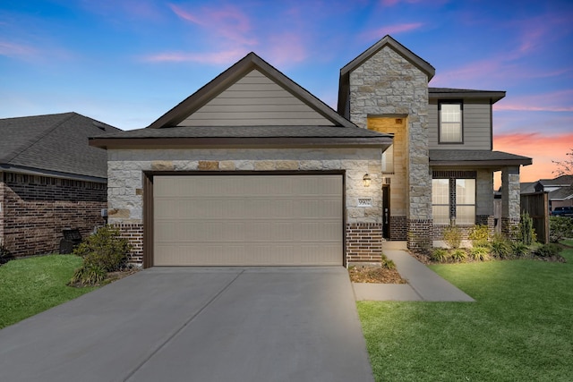 view of front facade featuring an attached garage, brick siding, a yard, stone siding, and concrete driveway