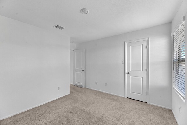 unfurnished bedroom with light colored carpet, visible vents, and baseboards