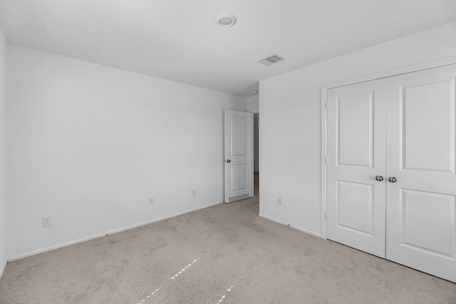 unfurnished bedroom with carpet floors, baseboards, visible vents, and a closet