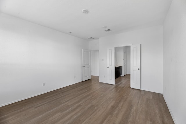 unfurnished bedroom with dark wood-style flooring, visible vents, and baseboards