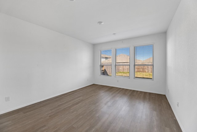 spare room featuring baseboards and dark wood-style flooring