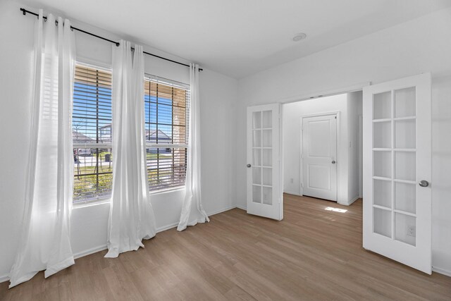 empty room featuring light wood-type flooring, baseboards, and french doors