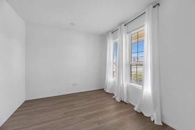 spare room featuring wood finished floors and baseboards