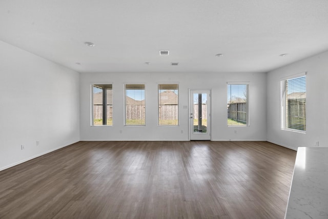 spare room featuring visible vents, baseboards, and dark wood-type flooring