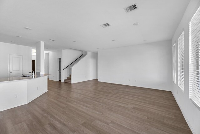 unfurnished living room featuring stairs, plenty of natural light, wood finished floors, and visible vents