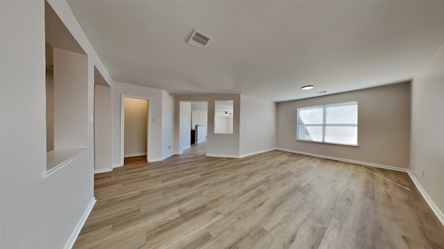 spare room with light wood-type flooring, visible vents, and baseboards