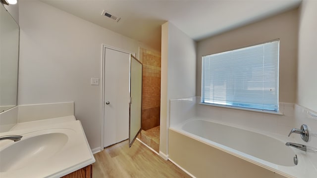 bathroom with a garden tub, wood finished floors, vanity, visible vents, and a tile shower