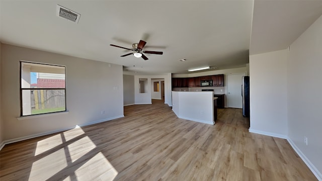 unfurnished living room featuring light wood-type flooring, visible vents, ceiling fan, and baseboards