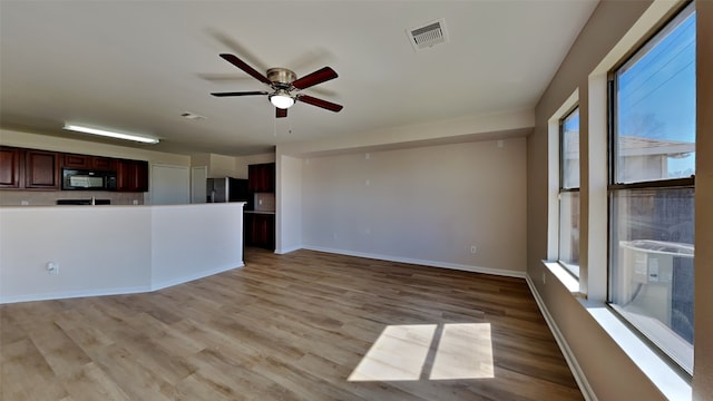 unfurnished living room featuring light wood-style floors, visible vents, baseboards, and a ceiling fan