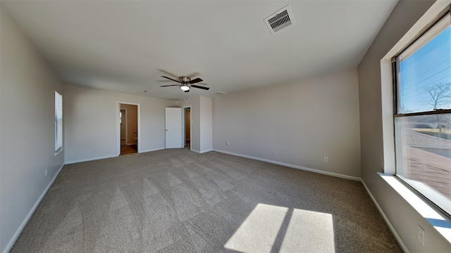 carpeted spare room with visible vents, ceiling fan, and baseboards