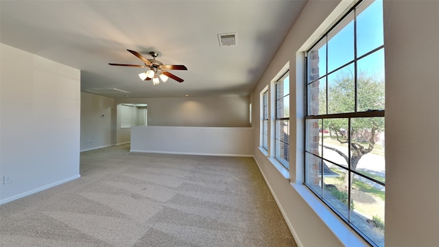 carpeted empty room featuring visible vents, ceiling fan, and baseboards