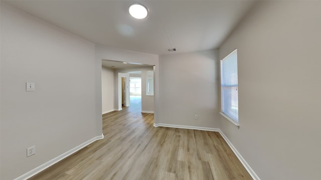 spare room featuring baseboards, visible vents, and light wood finished floors