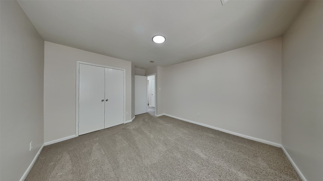 unfurnished bedroom with carpet, a closet, and baseboards