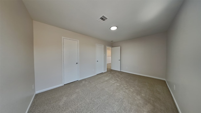 unfurnished bedroom with carpet floors, baseboards, and visible vents