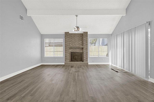 unfurnished living room with a wealth of natural light, visible vents, beam ceiling, and a fireplace