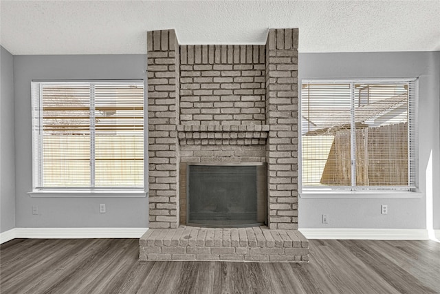 unfurnished living room featuring a fireplace, baseboards, and wood finished floors