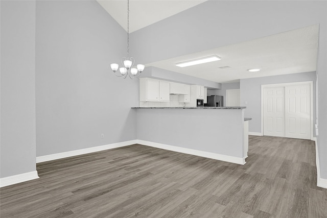 kitchen with stainless steel fridge, baseboards, a chandelier, wood finished floors, and white cabinets