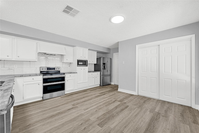 kitchen featuring visible vents, light wood-style flooring, stainless steel appliances, a textured ceiling, and white cabinetry