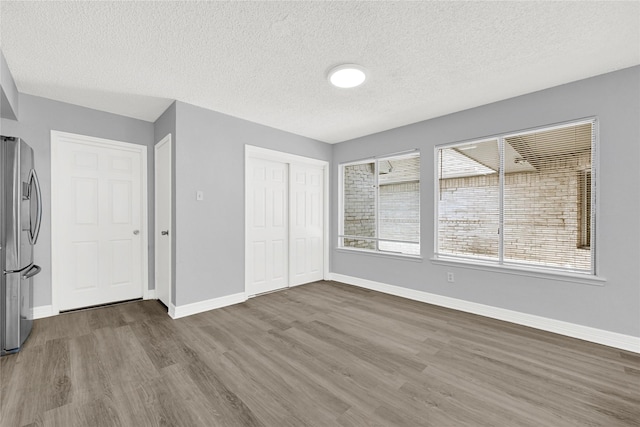 interior space with a closet, baseboards, stainless steel refrigerator with ice dispenser, and wood finished floors