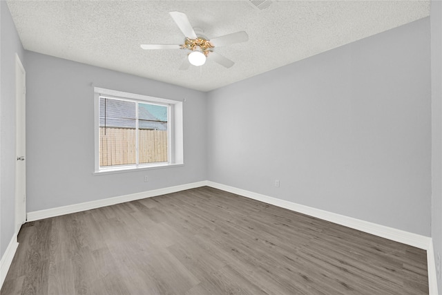 spare room with ceiling fan, dark wood-style floors, baseboards, and a textured ceiling