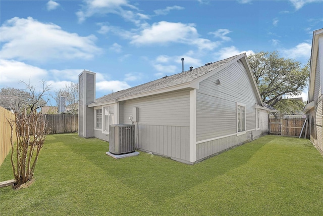 back of property with central air condition unit, a lawn, and a fenced backyard