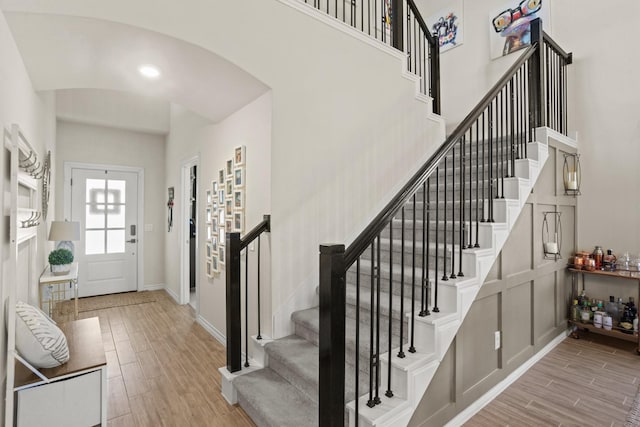 foyer featuring arched walkways, baseboards, a towering ceiling, and wood tiled floor