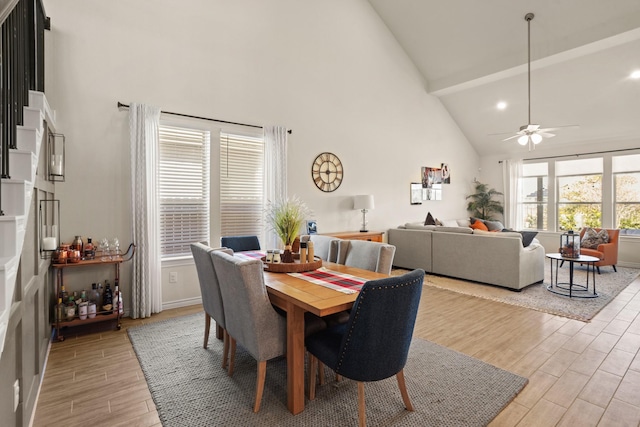 dining area featuring high vaulted ceiling, a ceiling fan, and wood tiled floor