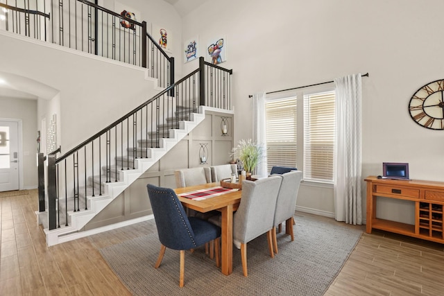 dining space with baseboards, stairway, a towering ceiling, and wood finished floors