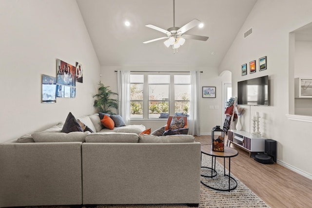 living area with visible vents, a ceiling fan, wood finished floors, high vaulted ceiling, and baseboards