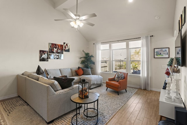 living area featuring lofted ceiling, light wood-type flooring, a ceiling fan, and baseboards