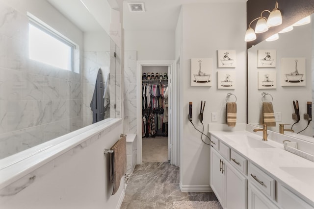 full bathroom featuring double vanity, visible vents, a spacious closet, a sink, and a walk in shower