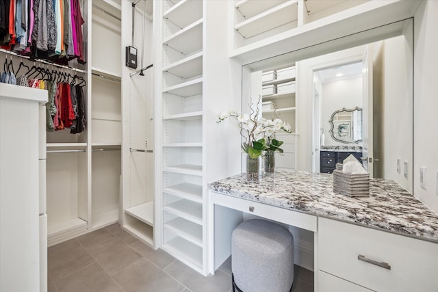 spacious closet featuring built in desk and tile patterned floors