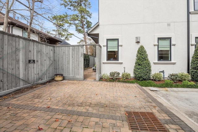 view of exterior entry featuring fence, a patio, and stucco siding