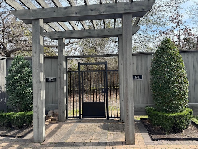 view of gate featuring fence and a pergola