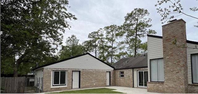 rear view of house with brick siding, fence, and a patio