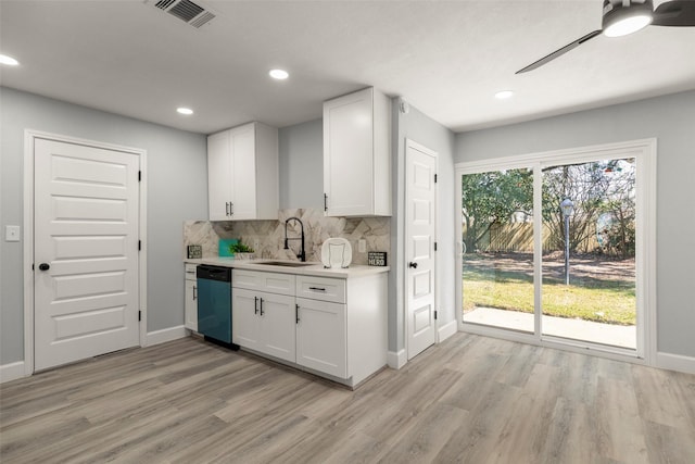 kitchen featuring light wood finished floors, decorative backsplash, dishwashing machine, light countertops, and a sink