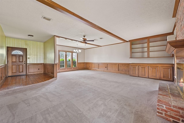 unfurnished living room featuring a wainscoted wall, carpet floors, a textured ceiling, and visible vents