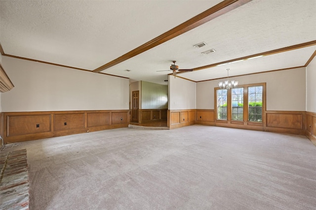 empty room with a textured ceiling, light colored carpet, a wainscoted wall, visible vents, and beam ceiling