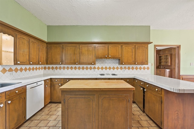 kitchen featuring dishwasher, a peninsula, a kitchen island, and brown cabinets