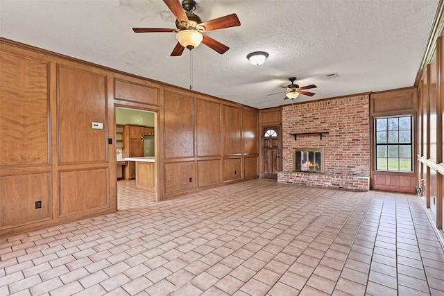 unfurnished living room featuring light tile patterned floors, visible vents, a brick fireplace, ceiling fan, and wooden walls