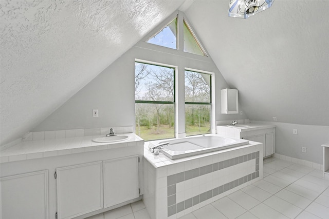 bathroom featuring a textured ceiling, vaulted ceiling, a garden tub, and vanity