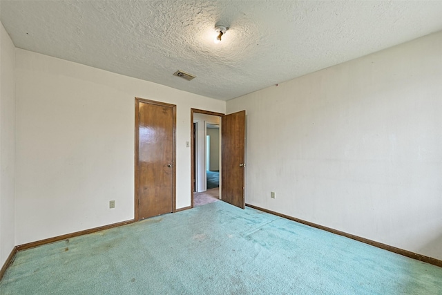 unfurnished bedroom with baseboards, a textured ceiling, visible vents, and carpet flooring