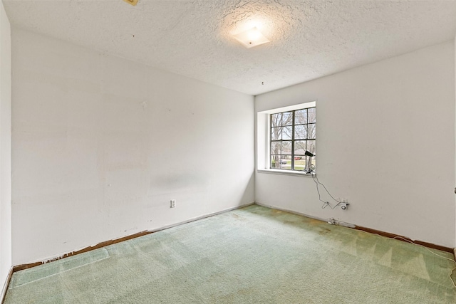 unfurnished room with a textured ceiling, carpet floors, and baseboards