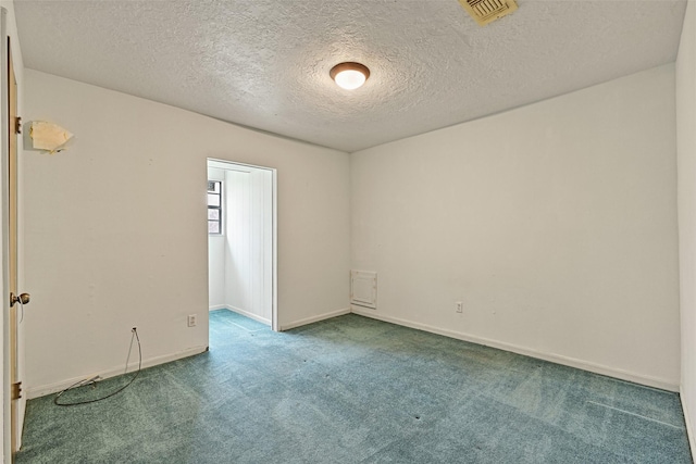 unfurnished room featuring a textured ceiling, carpet, visible vents, and baseboards