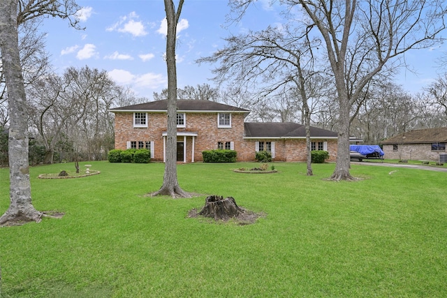 view of front facade with brick siding and a front lawn