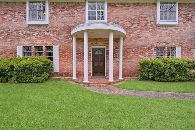 entrance to property with a yard and brick siding